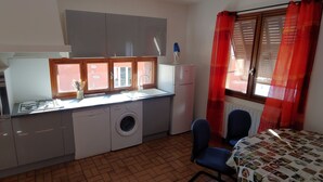 Une cuisine compacte équipée d’un lave-linge, d’une cuisinière et d’un réfrigérateur.