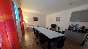 Un espace de vie compact comprenant une table à manger, des chaises, un canapé, un téléviseur et un coin cuisine.