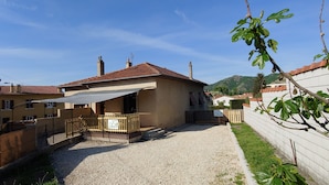 Un immeuble résidentiel avec une allée en gravier, un patio clos et une vue sur une colline.