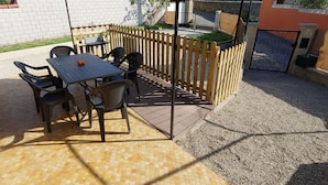 Un espace extérieur aménagé avec une table et des chaises, une clôture en bois et une entrée fermée par un portail.