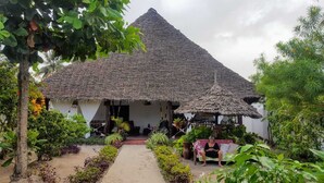 Ein Haus mit einem Strohdach und einem Gartenweg, der zu einer Sitzgruppe führt.