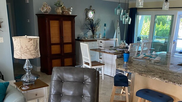 Uma sala de estar moderna com uma poltrona de couro, uma área de jantar com banquetas altas e uma cozinha com uma ilha grande.