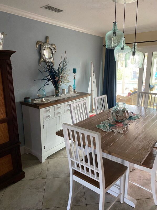 Un comedor con una mesa de madera, sillas blancas, un armario blanco y adornos decorativos.
