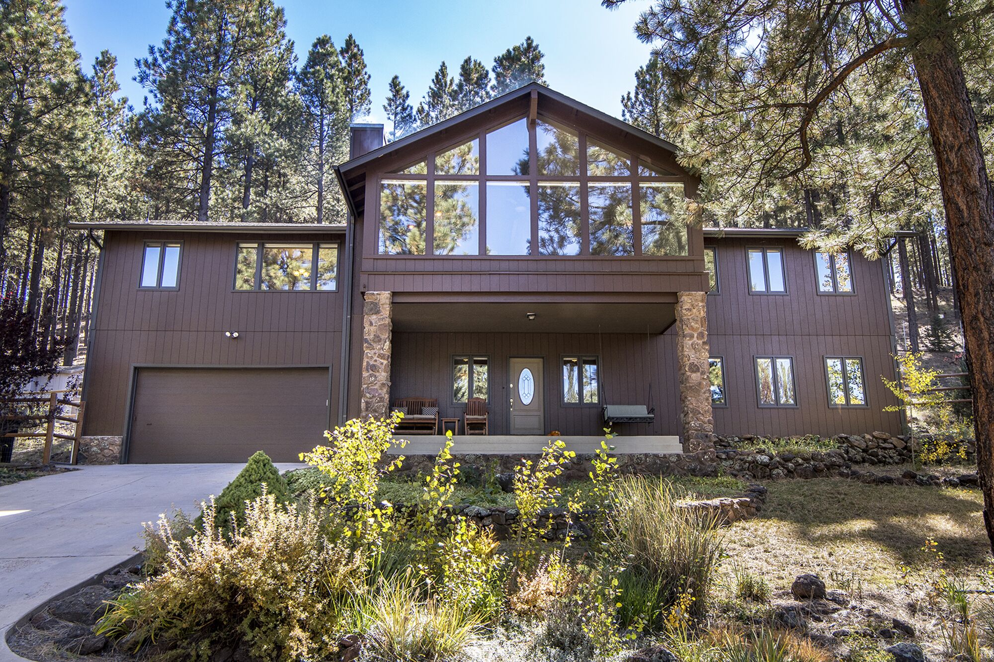 A two-story house with a large front porch, stone pillars, and a garage.