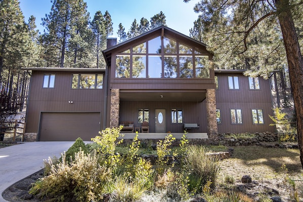 A two-story house with a large front porch, stone pillars, and a garage.