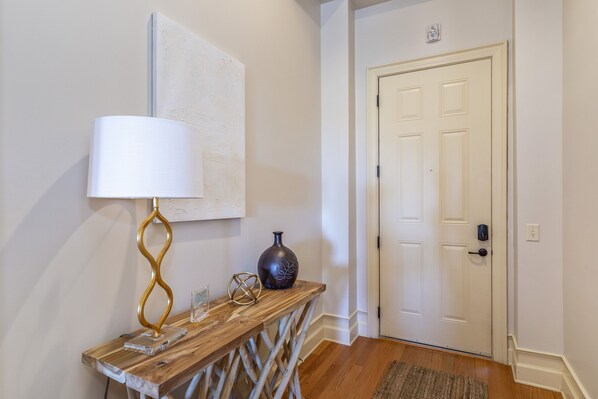 A wooden console table with a lamp, vase, and decorative items in a hallway with a white door and textured wall. - Stoneview Sunset- Amazing Waterfront Views!!! (Dadeville)