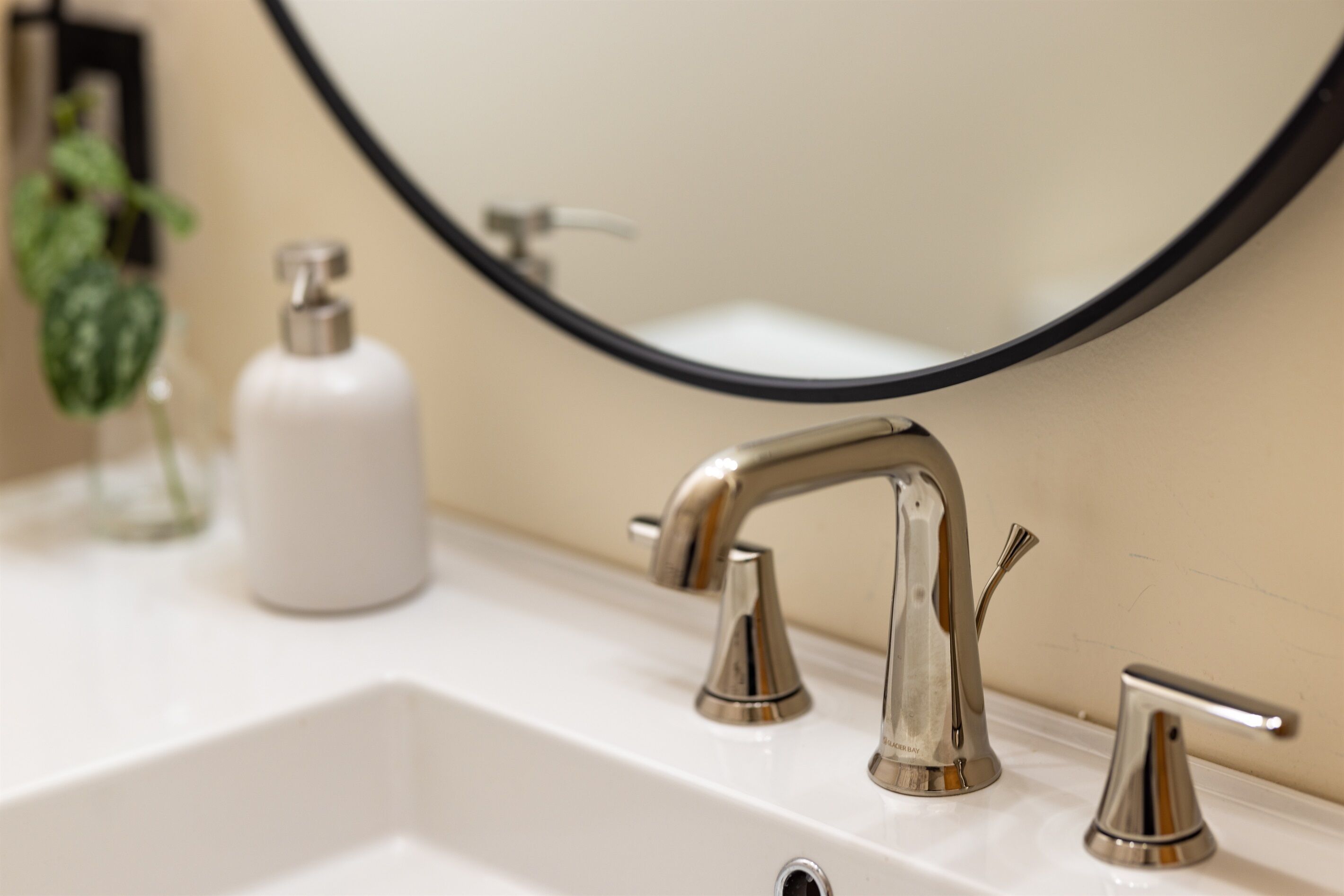 A bathroom sink with a modern faucet and a soap dispenser.