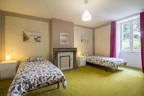 A room with two beds, a fireplace, and a window with curtains.