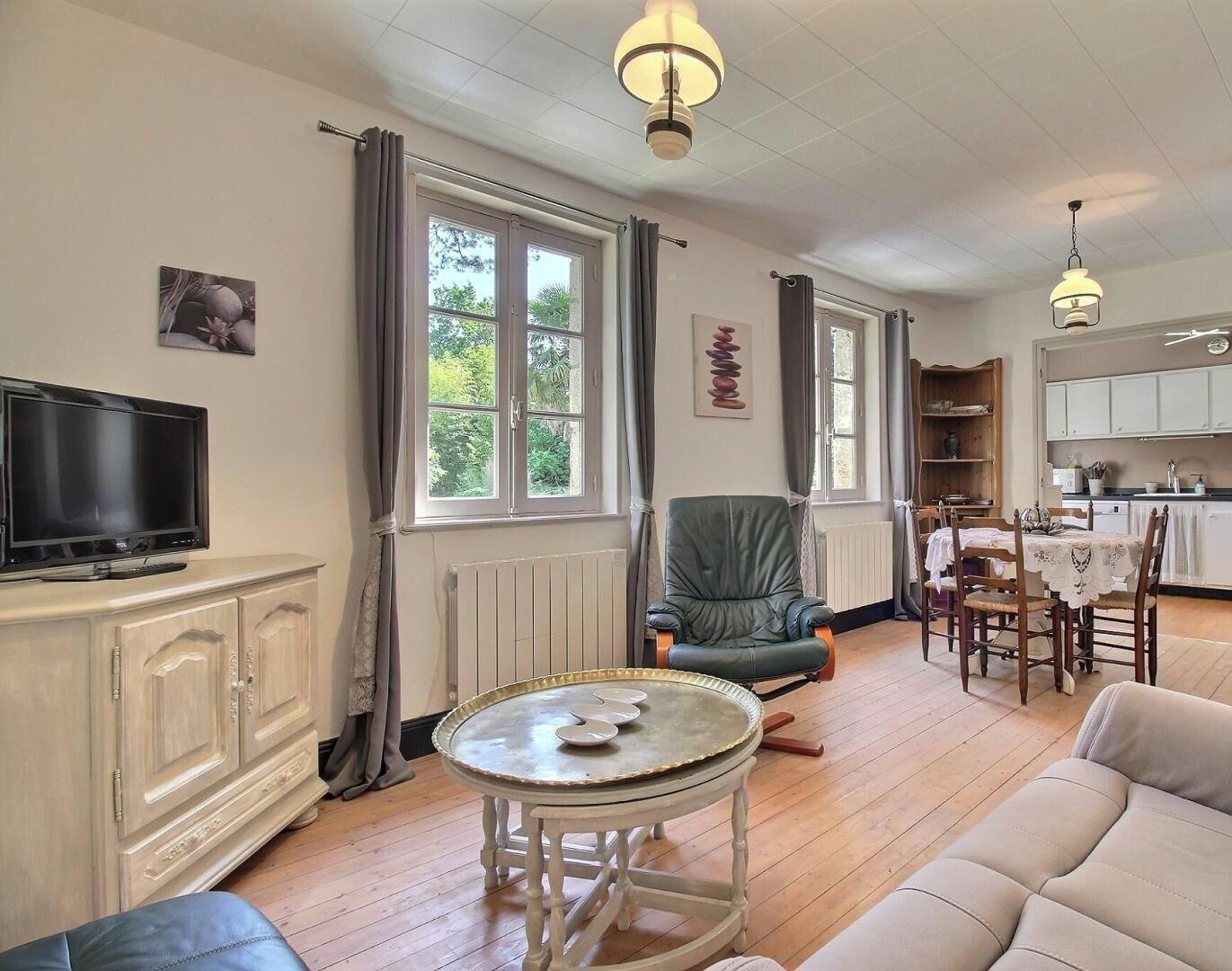 A living room with a television, a dining area with a table and chairs, and a kitchen area.