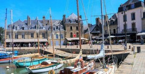 A harbor with boats docked, a building with shops, and a pedestrian walkway.