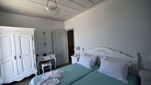 A bedroom with a bed, two nightstands, a dresser, and a hanging light fixture. - Heliades maisonettes (Lesvos)