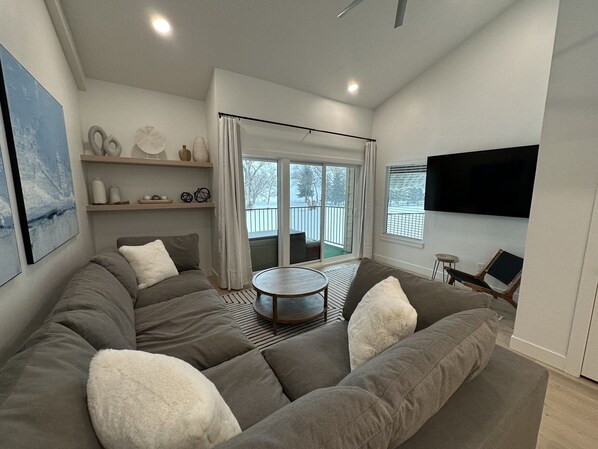 A modern living room with a sectional sofa, a round coffee table, and a TV mounted on the wall.