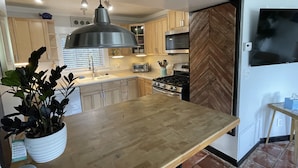 A kitchen with wooden cabinets, a stainless steel stove, a sink, and a hanging light fixture. - Rock Ridge lll.  Close to everything. (Vero Beach)