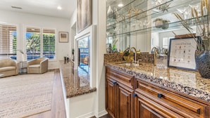 A modern kitchen with granite countertops, wooden cabinets, and a large glass backsplash.