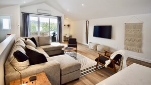 Un salon moderne avec un canapé, des fauteuils, une table basse et un téléviseur.