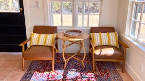 Una habitación con dos sillones de cuero marrón, una mesita redonda y una alfombra estampada.