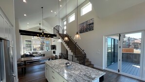 Una cocina amplia con una isla grande, un comedor y una escalera que lleva a un balcón.