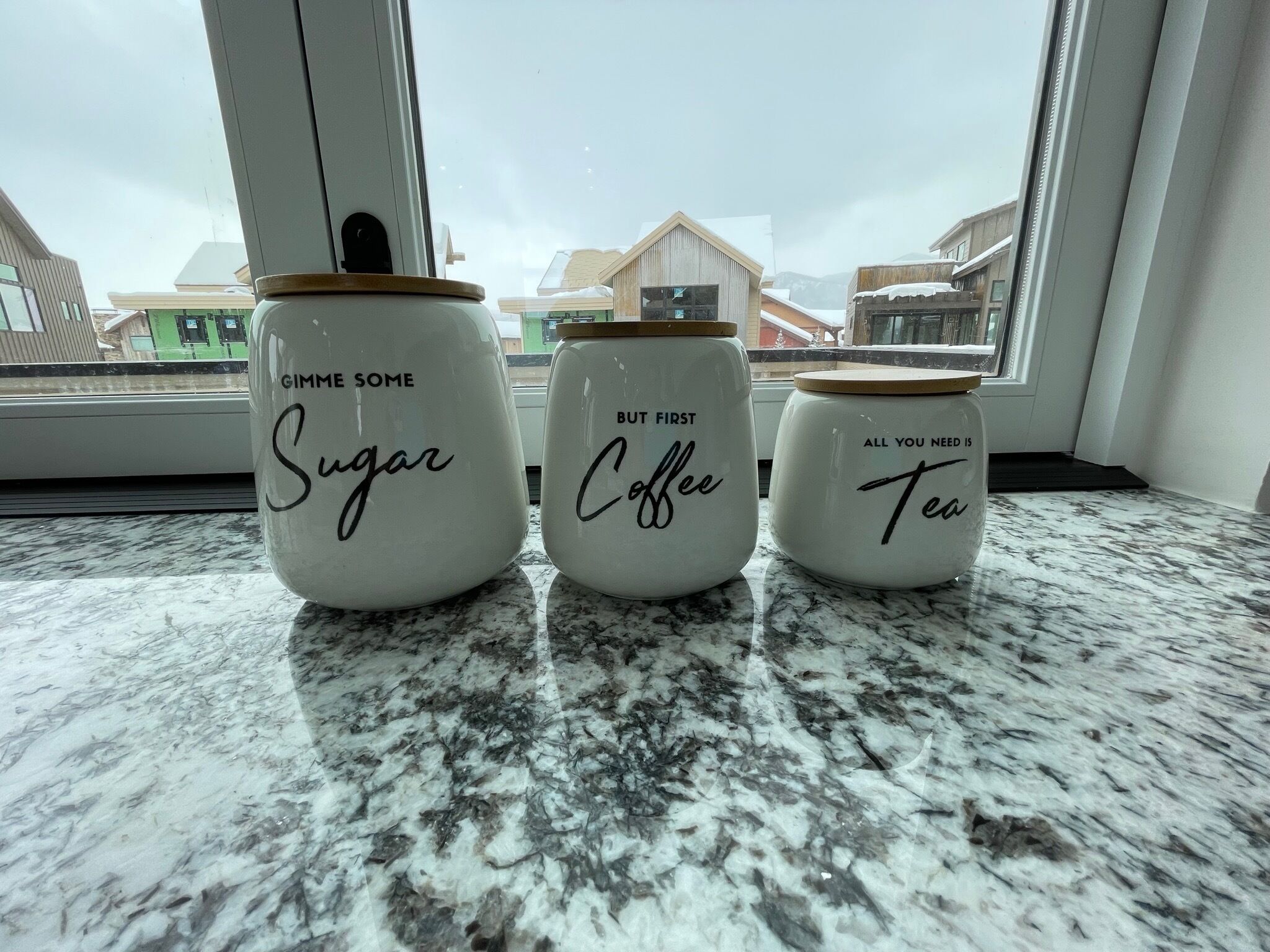 Three jars on a kitchen counter with labels 'Sugar,' 'Coffee,' and 'Tea.'