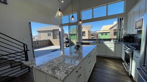 Una cocina moderna con una isla grande, armarios blancos y vistas del vecindario.