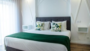Een moderne slaapkamer met een groot bed, een groene plaid en decoratieve kussens.