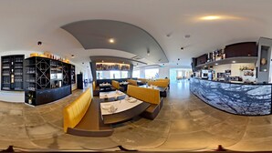 Een moderne bar met zitplaatsen, een toonbank en planken met flessen en glazen.