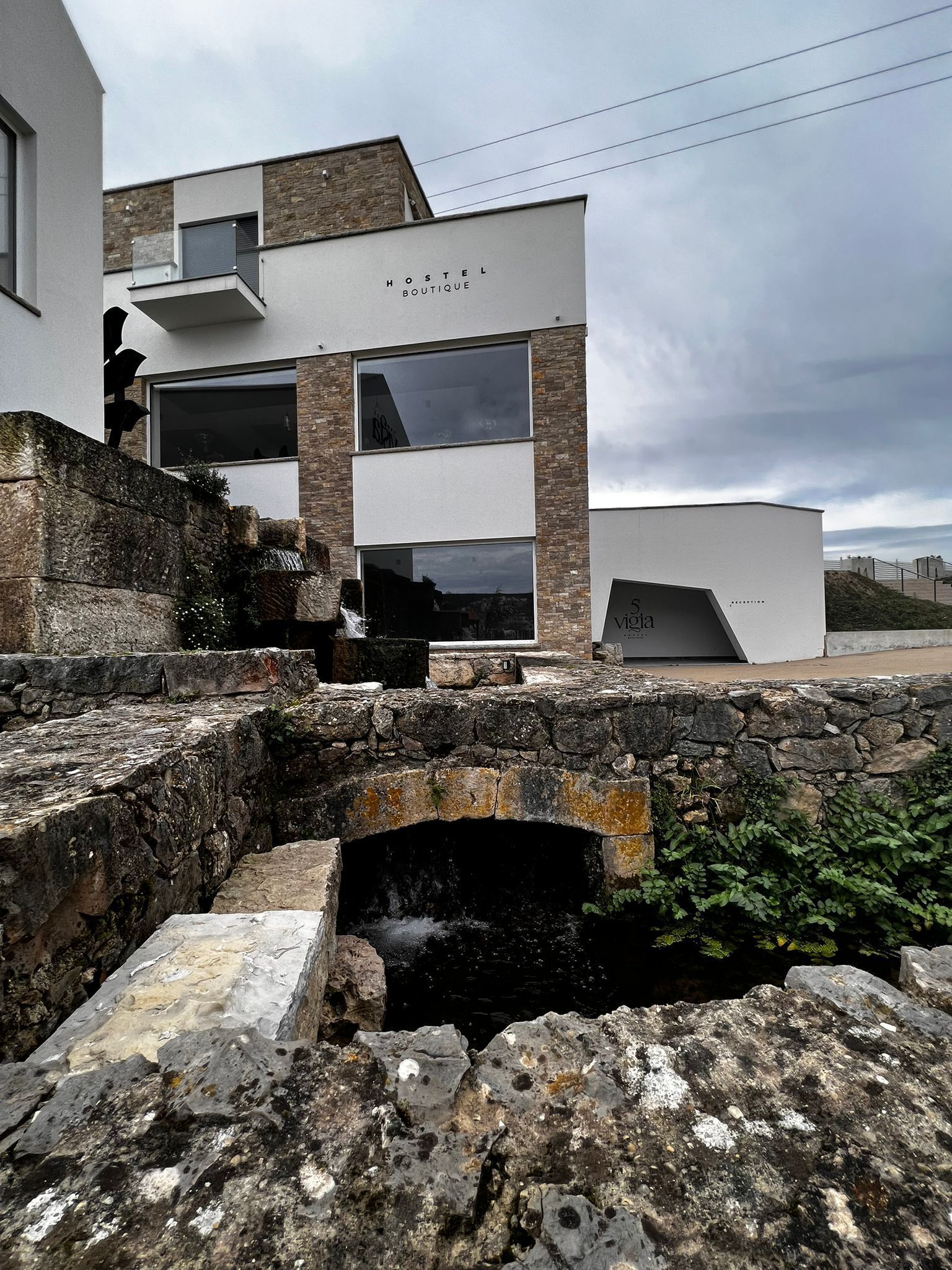 Un edificio moderno con un puente de piedra, con la inscripción 