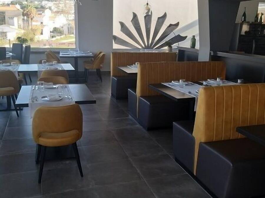 Un ristorante moderno con tavoli alti e banquette, una grande parete decorativa e vista all'esterno.