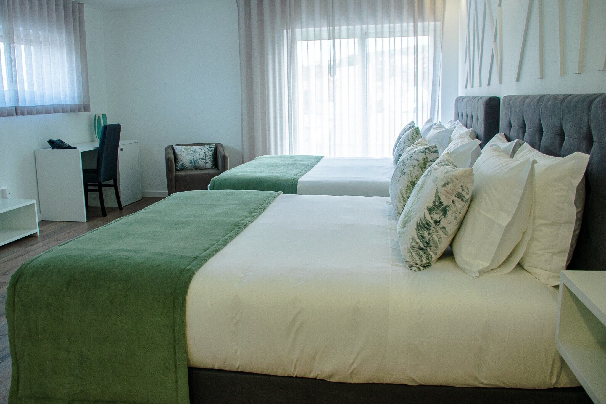 A hotel room with two beds, a desk, and a chair.