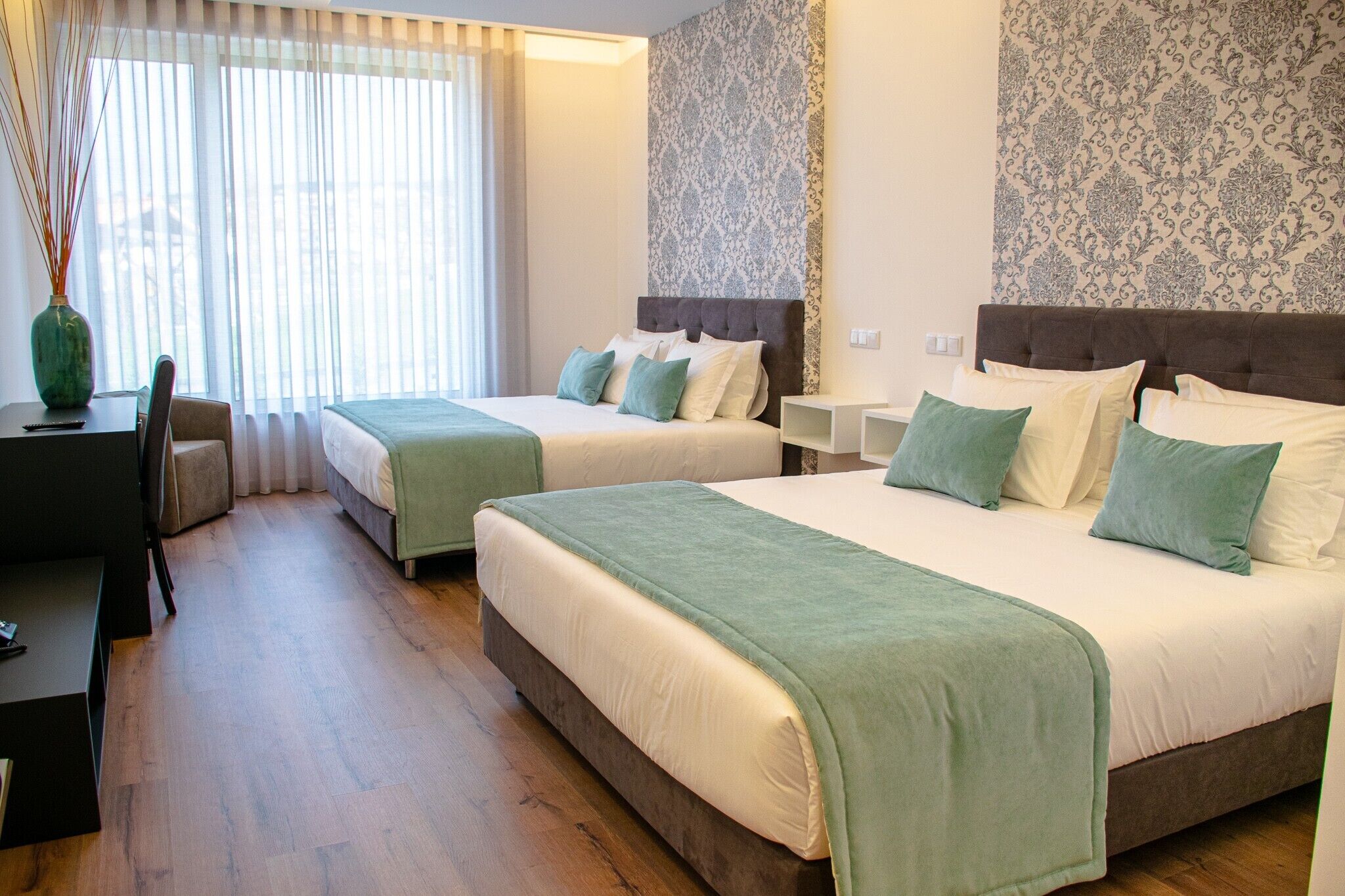 Een hotelkamer met twee bedden, een bureau en een stoel.