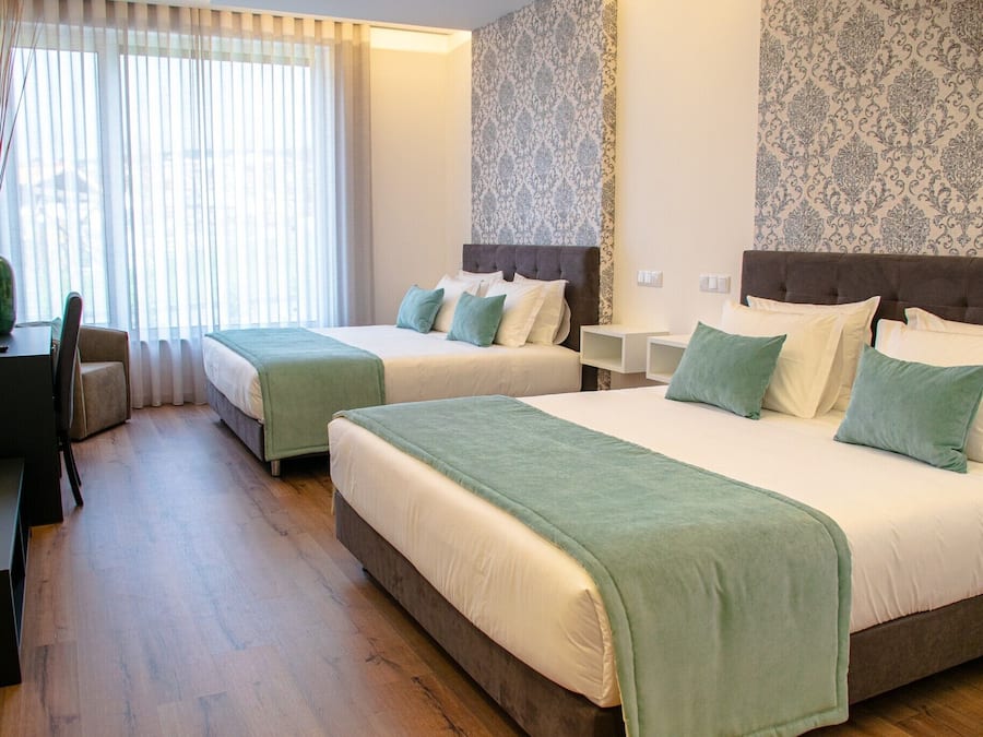 Een hotelkamer met twee bedden, een bureau en een stoel.
