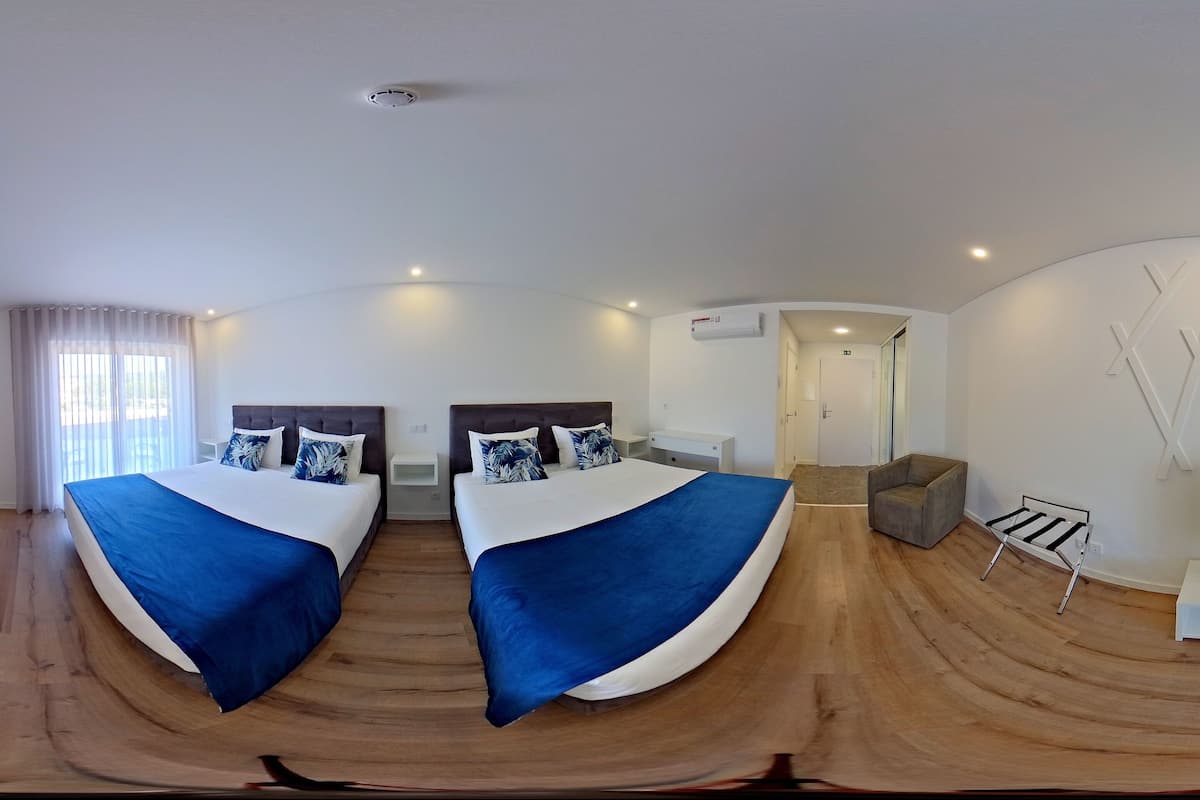 Ett modernt hotellrum med två sängar, en TV, ett skrivbord och en stol.
