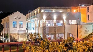 Een gebouw met de borden 'Vista Restaurant' en '5 Vigia Guest House', met een modern ontwerp, meerdere verdiepingen en grote ramen.