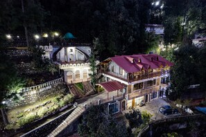 Ein großes, mehrgeschossiges Gebäude mit rotem Dach, umgeben von Bäumen und einer Steinmauer.