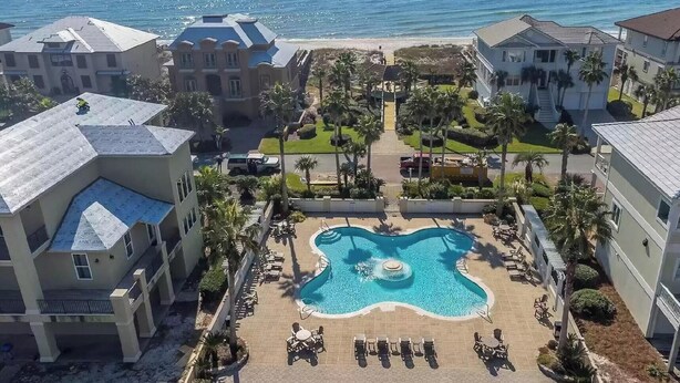 A resort with a central swimming pool, multiple buildings, and a beach view. - Calvert Castle, Elevator, Golf cart, Beach ,Pool (gulf shores)