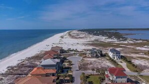 A coastal residential area with beachfront properties, including houses with red roofs and a large white building with a balcony. - Calvert Castle, Elevator, Golf cart, Beach ,Pool (gulf shores)