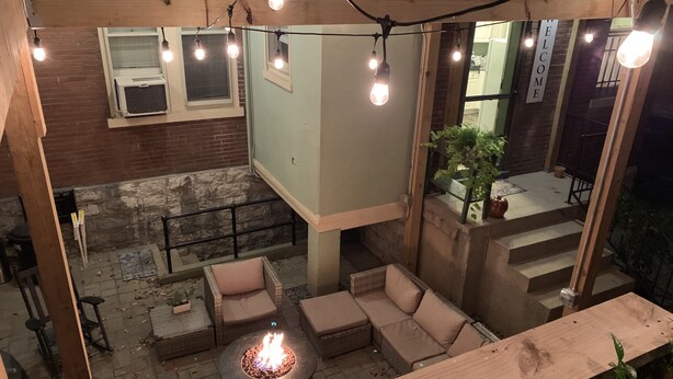 An outdoor patio area with a fire pit, seating, and string lights. - The Kentucky Rose - Old Louisville with deck and courtyard (Louisville)