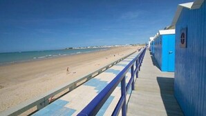 A beachside walkway with a wooden deck and a blue building with a door. - Villa "Le Paradis Bleu" Heated pool and beach 200 m'away (Saint-Gilles-Croix-de-Vie)