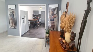 A modern kitchen with grey cabinets, a wooden dining table, and a view into the dining area. - Villa "Le Paradis Bleu" Heated pool and beach 200 m'away (Saint-Gilles-Croix-de-Vie)