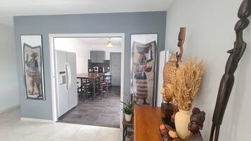 A modern kitchen with grey cabinets, a wooden dining table, and a view into the dining area.