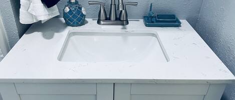 A bathroom with a white sink, a soap dispenser, and a 'No Smoking' sign.