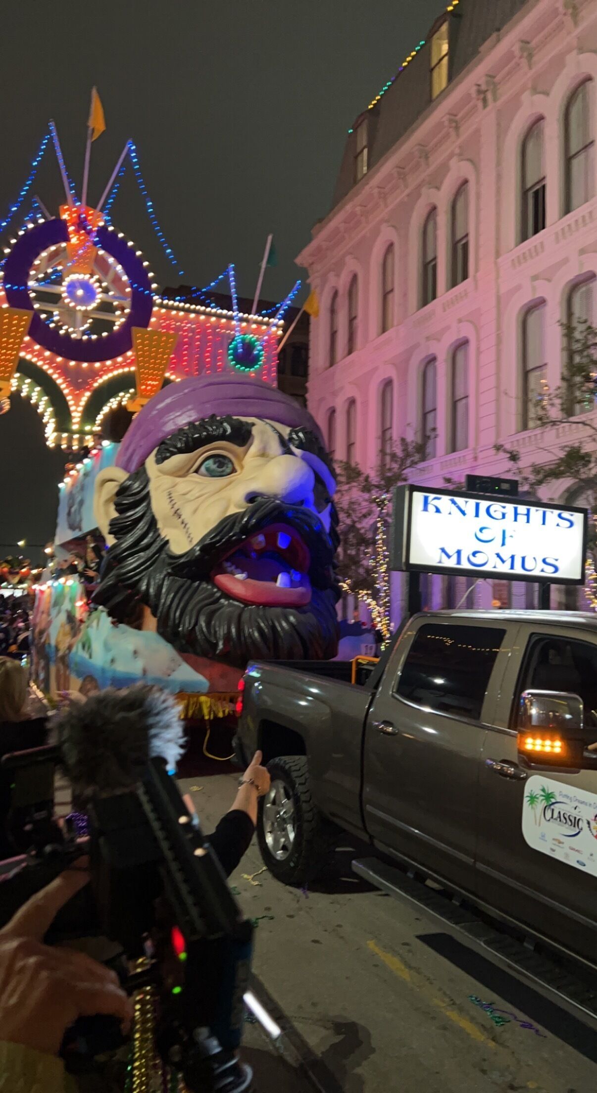 A parade float with a large, colorful lion head and a sign that reads 'KNIGHTS OF MOMUS.'