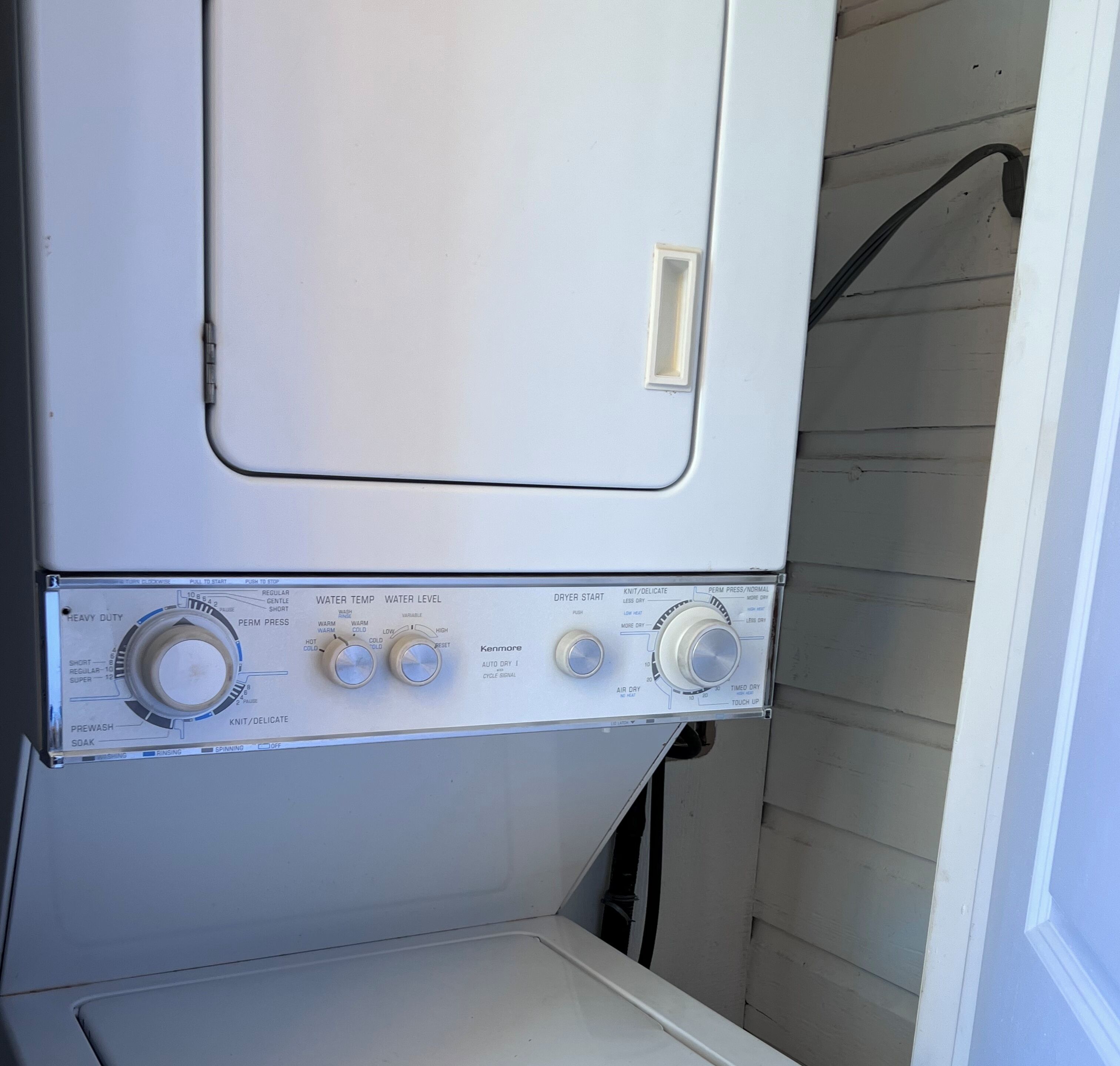 A Kenmore washer with control knobs for water temperature, water level, and drying options.