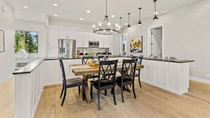 Une cuisine moderne avec des meubles blancs, un îlot central et des luminaires suspendus.