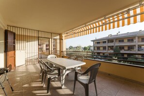 A balcony with a table and chairs, a grill, and a view of buildings. - Sunflower Apartment - 2 bedrooms with pool, air conditioned and Wifi (Sirmione)