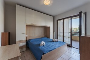 A bedroom with a bed, a wardrobe, a desk, and a balcony with curtains. - Sunflower Apartment - 2 bedrooms with pool, air conditioned and Wifi (Sirmione)