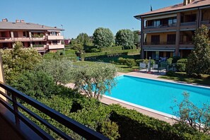 A pool surrounded by lush greenery and multi-story buildings. - Sunflower Apartment - 2 bedrooms with pool, air conditioned and Wifi (Sirmione)