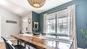 A dining area with a wooden table, black chairs, and a window with patterned curtains. - Isle of the Pines, 1 mile from The Village of Pinehurst! (Pinehurst)
