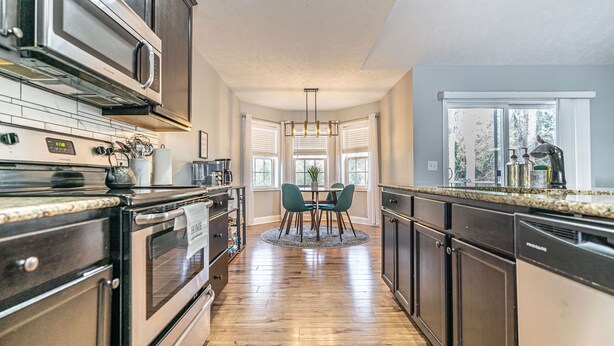 A modern kitchen with dark cabinetry, stainless steel appliances, and a wooden floor. - Isle of the Pines, 1 mile from The Village of Pinehurst! (Pinehurst)