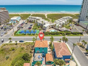 Ein Hotel an der Küste mit Blick auf den Strand, einem Parkplatz und einem Tennisplatz.