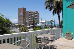 Ein Hotel mit auffälliger Beschilderung, einem Balkon mit Sitzgelegenheiten und Blick auf die Straße und das Meer.